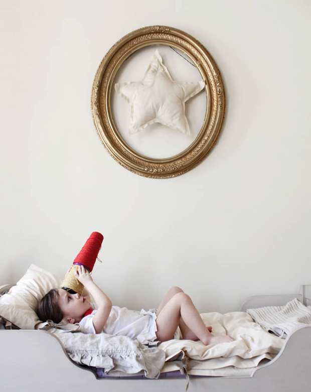 Little girl in her bedroom playing with a star shaped pillow