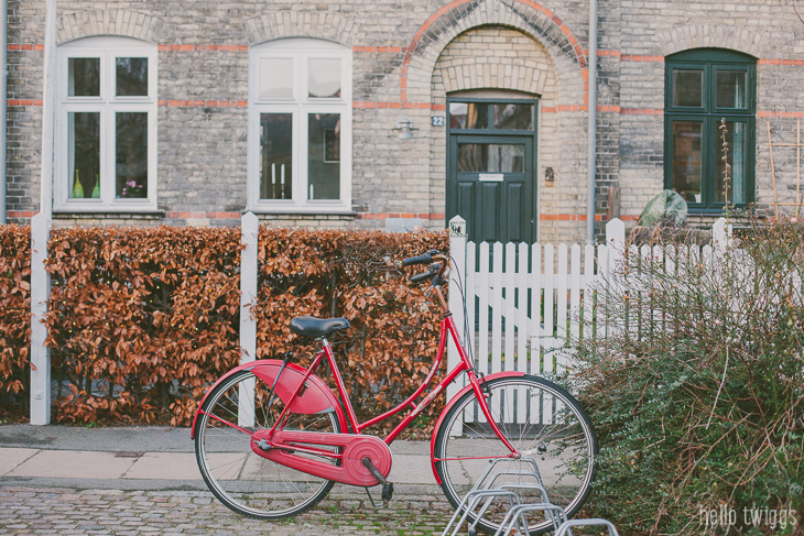 Red Bike parked against white fence in Copenhagen